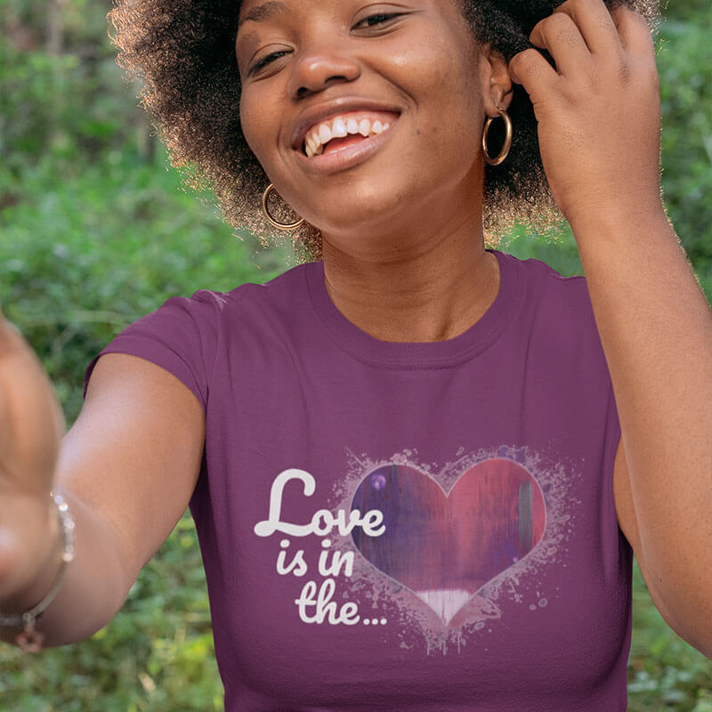 Woman smiling wearing a purple Love is in the Heart t-shirt.