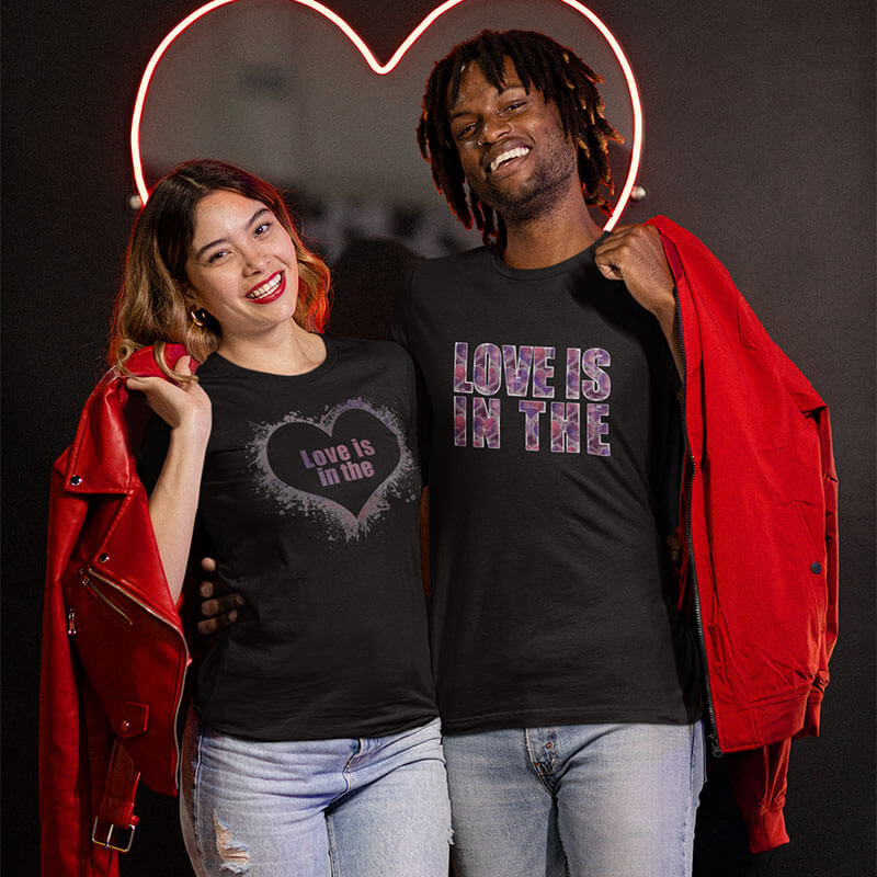 Couple smiling wearing black Love is in the Heart t-shirts.