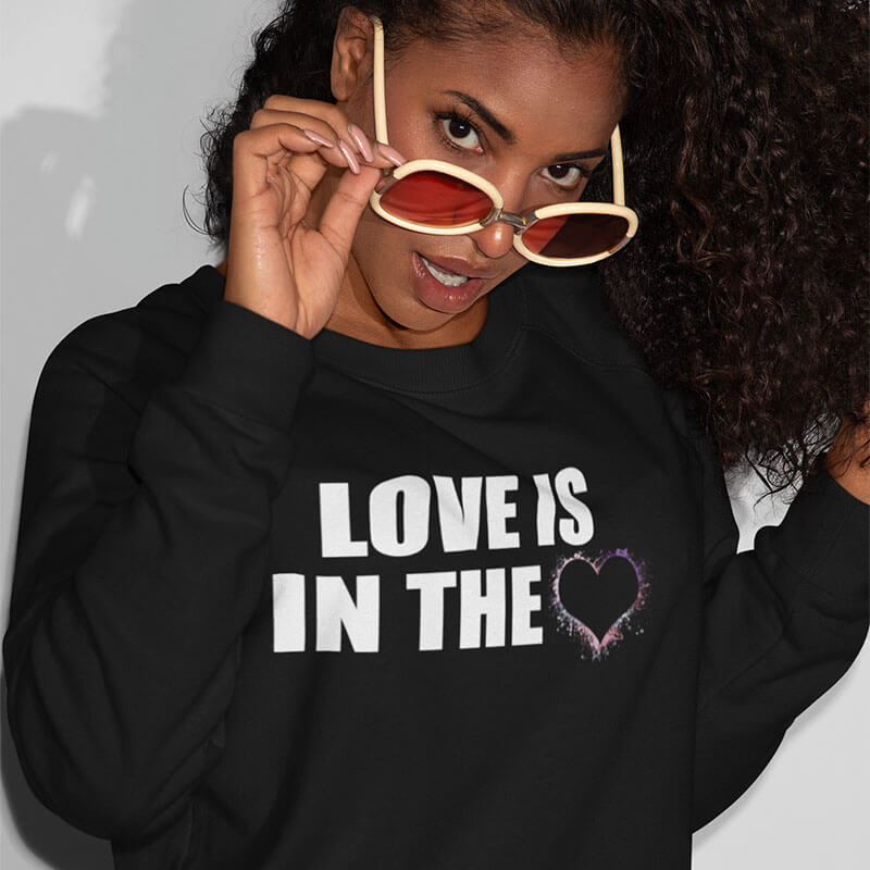 Woman with glasses wearing a black Love is in the Heart t-shirt.